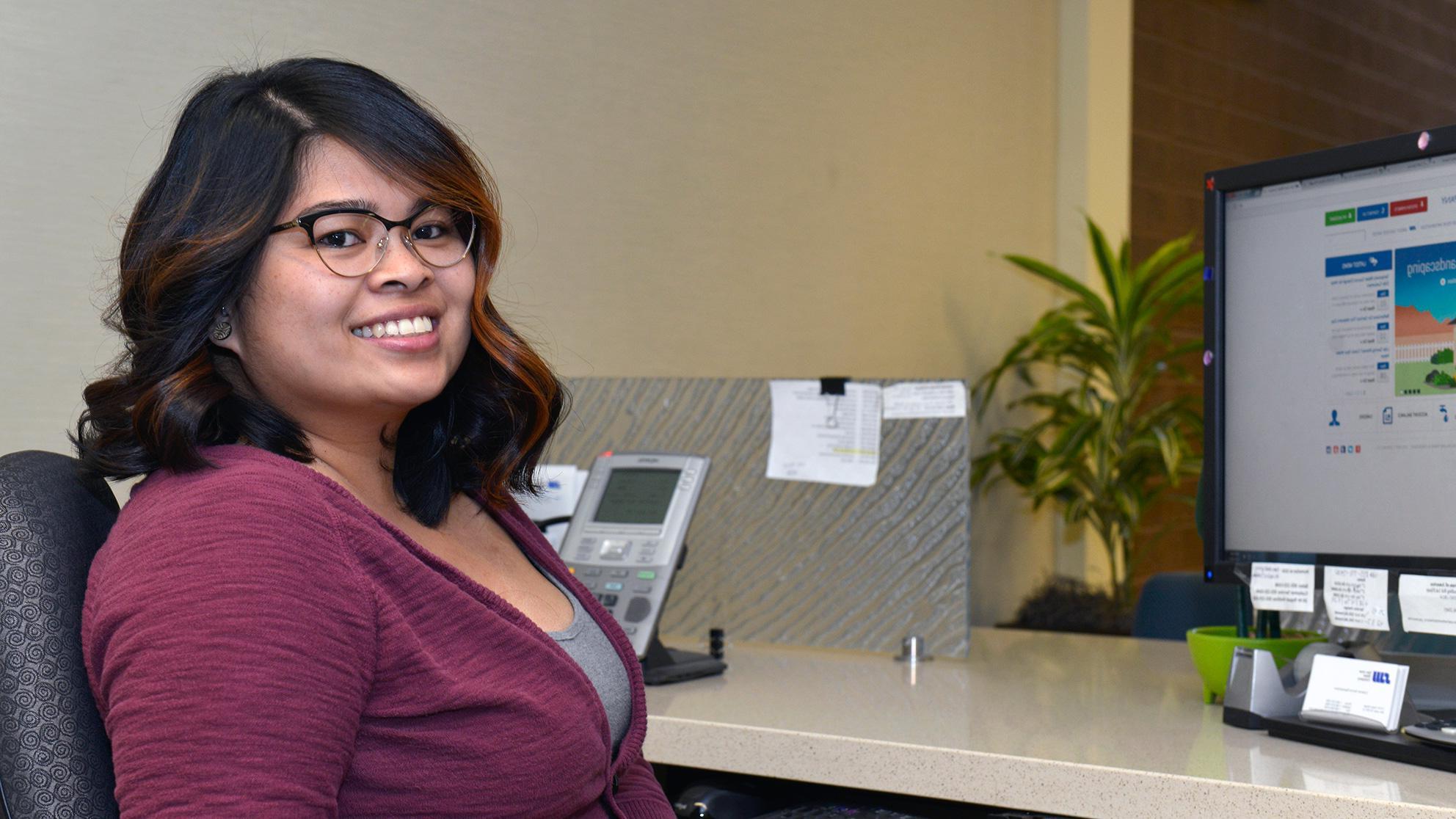 Smiling woman at her desk with a computer in the background